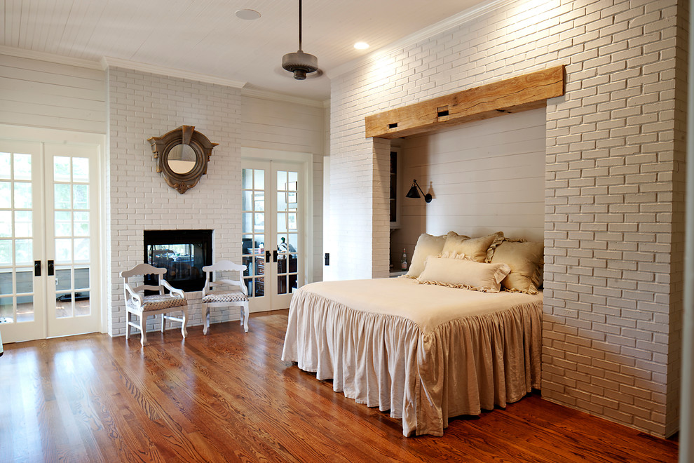 Пример оригинального дизайна: спальня в стиле кантри с серыми стенами, темным паркетным полом, двусторонним камином и фасадом камина из кирпича