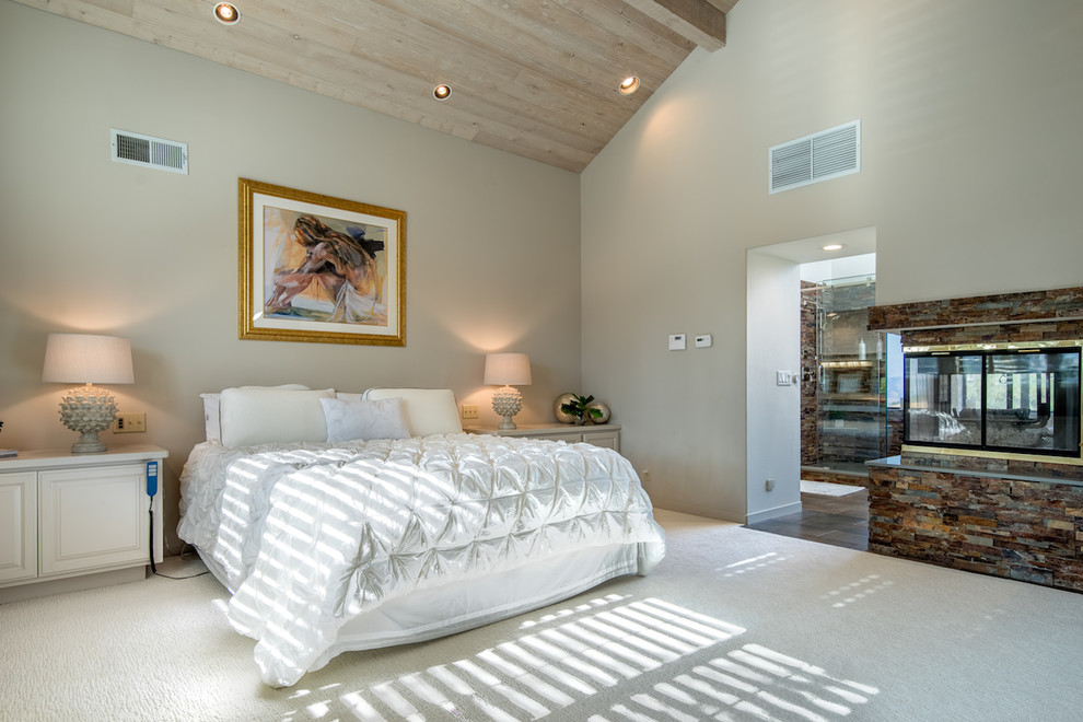 サンフランシスコにある広いコンテンポラリースタイルのおしゃれな主寝室 (グレーの壁、カーペット敷き、両方向型暖炉、石材の暖炉まわり、白い床) のインテリア