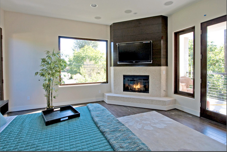 Foto de dormitorio contemporáneo de tamaño medio con paredes beige, suelo de madera oscura, chimenea de esquina y marco de chimenea de baldosas y/o azulejos
