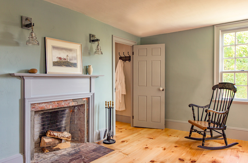 Inspiration for a mid-sized farmhouse master light wood floor bedroom remodel in Boston with blue walls, a standard fireplace and a brick fireplace