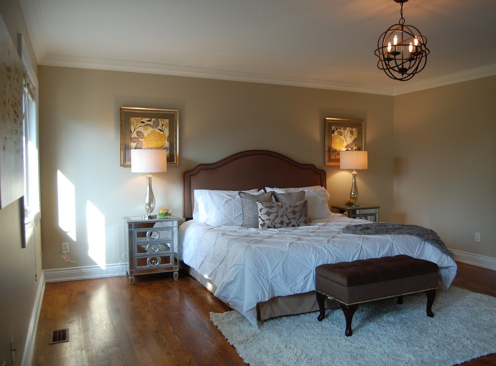 Cette image montre une grande chambre parentale traditionnelle avec un mur beige et un sol en bois brun.