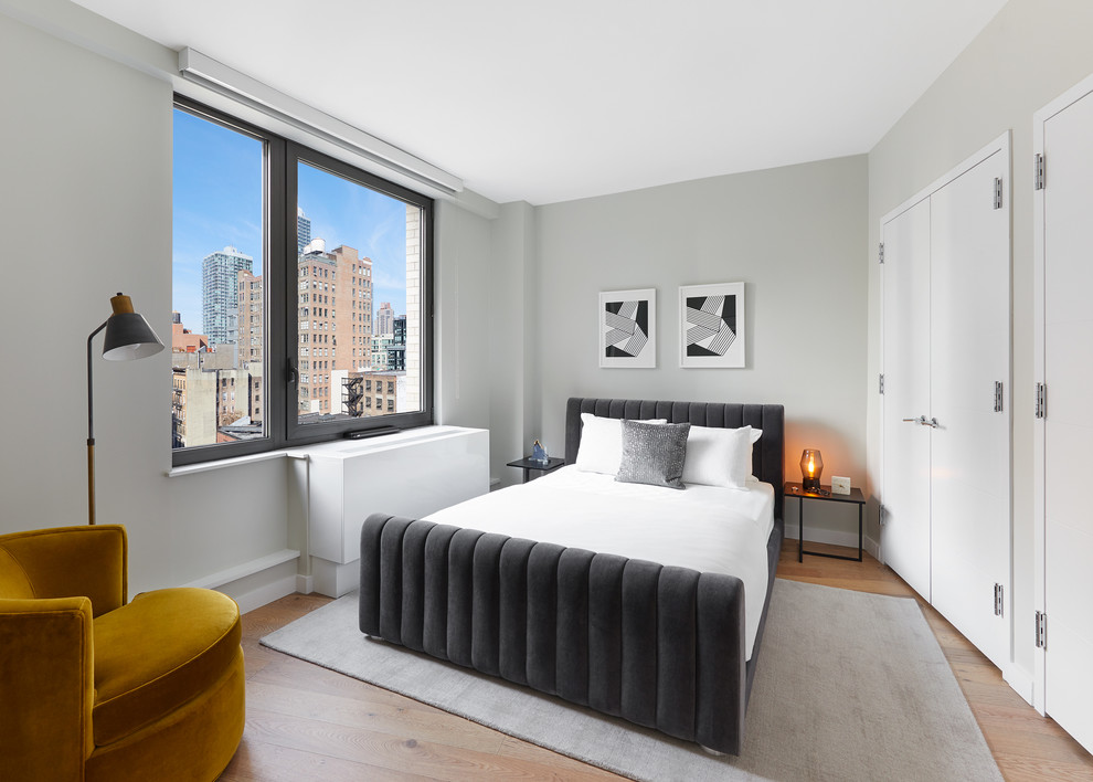 ニューヨークにあるコンテンポラリースタイルのおしゃれな客用寝室 (グレーの壁、淡色無垢フローリング、ベージュの床) のインテリア