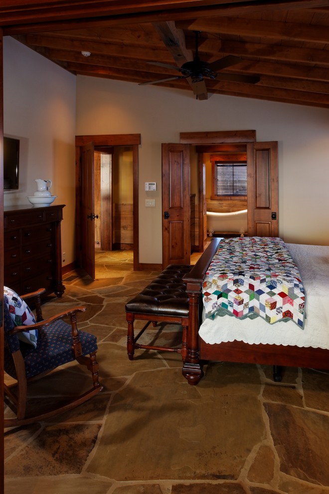 Modelo de dormitorio principal rural extra grande con paredes beige y suelo de pizarra
