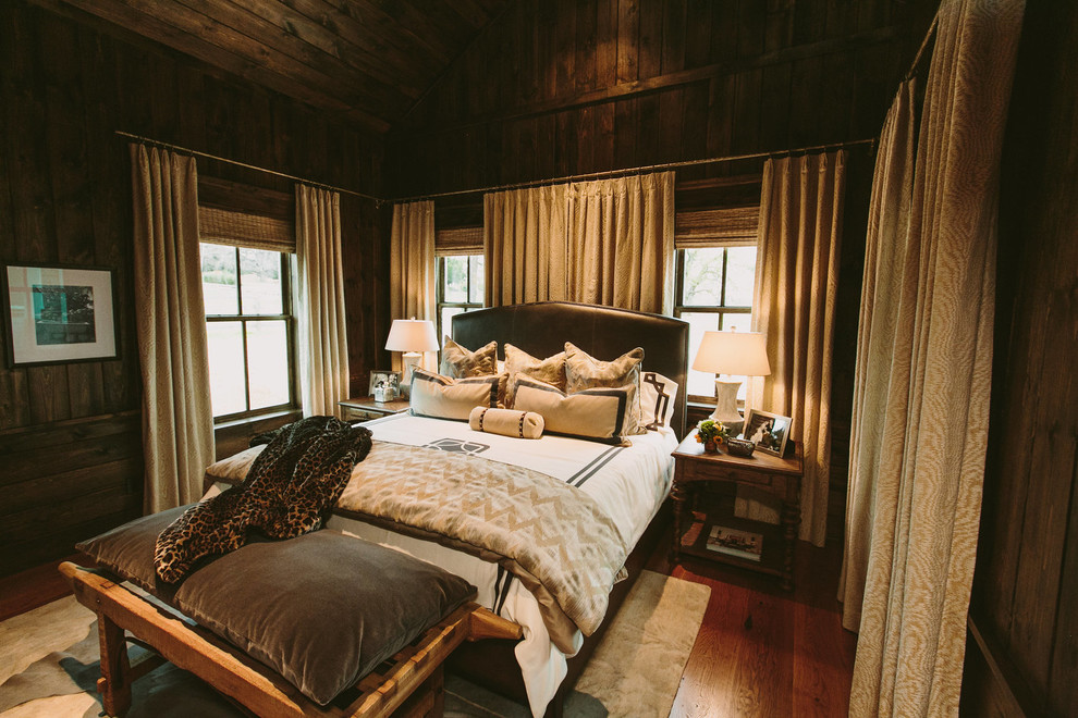 Modelo de dormitorio principal rural de tamaño medio sin chimenea con paredes marrones y suelo de madera oscura