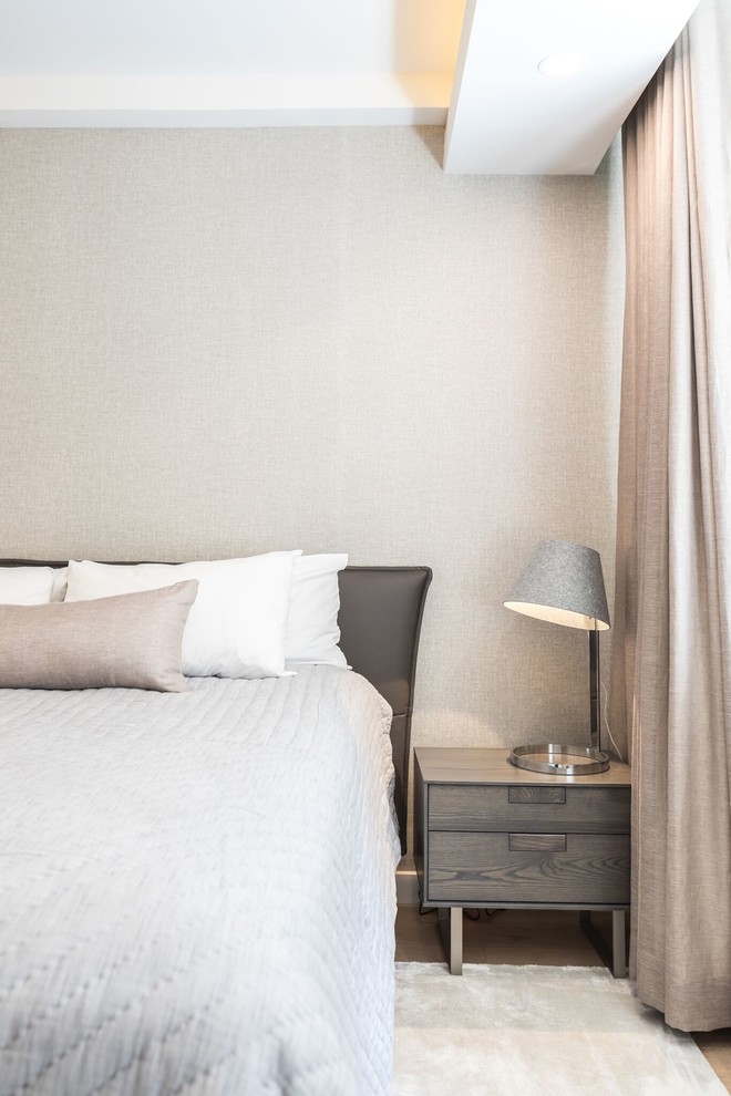 Imagen de dormitorio principal minimalista de tamaño medio sin chimenea con paredes grises, suelo de madera clara y suelo beige