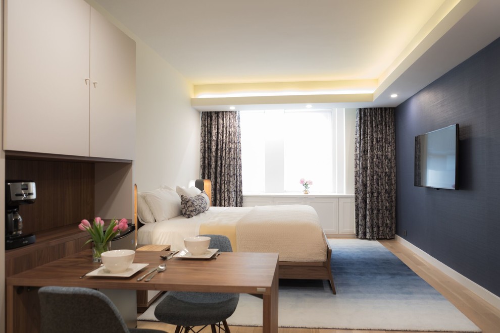 Modelo de habitación de invitados minimalista pequeña sin chimenea con paredes azules, suelo de madera clara y suelo azul