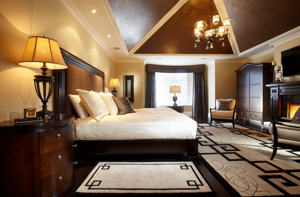 Großes Klassisches Hauptschlafzimmer mit beiger Wandfarbe, Kamin, dunklem Holzboden und Kaminumrandung aus Holz in Toronto