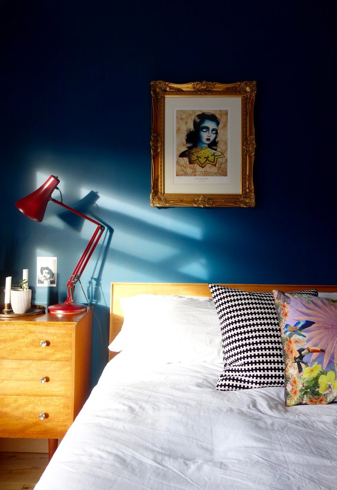 Diseño de dormitorio principal retro de tamaño medio con paredes azules y suelo de madera clara