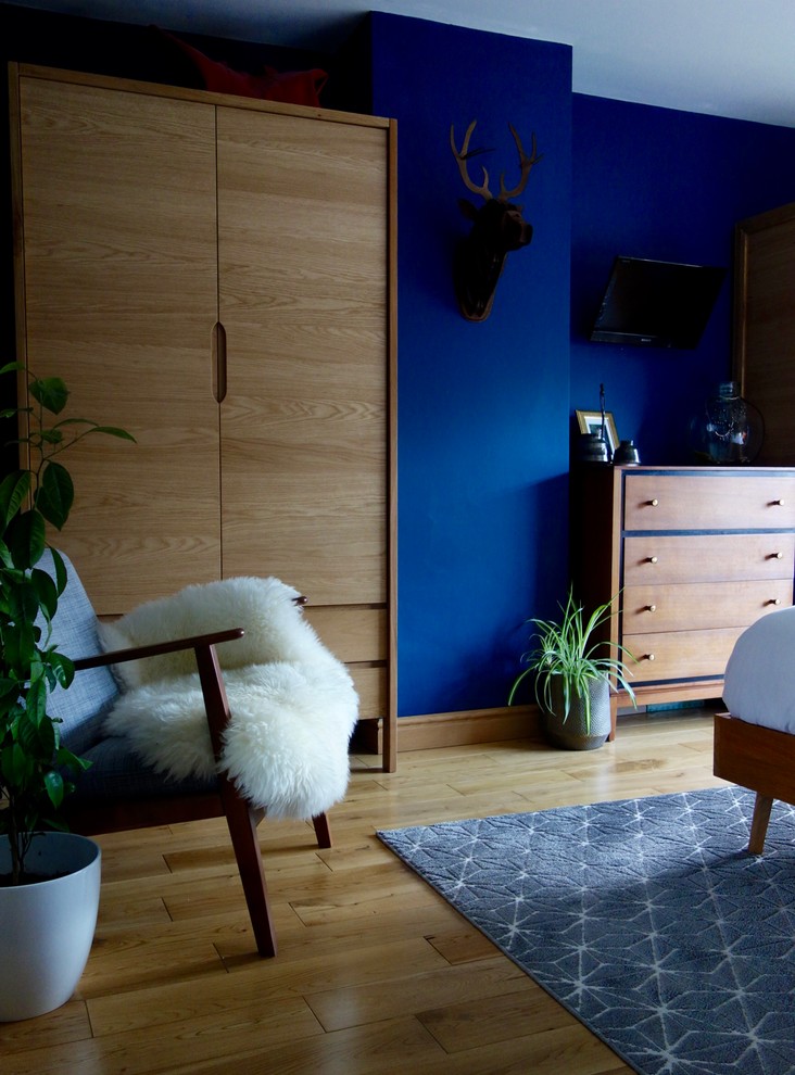 Mittelgroßes Mid-Century Hauptschlafzimmer mit blauer Wandfarbe und hellem Holzboden in Sonstige