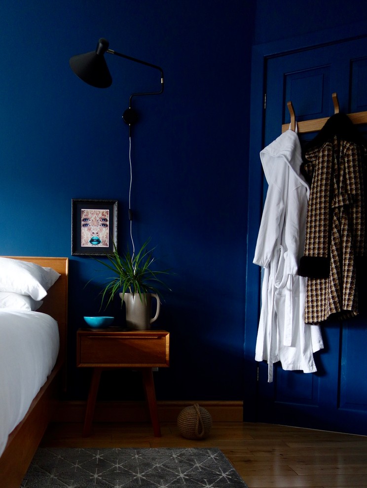 Aménagement d'une chambre parentale rétro de taille moyenne avec un mur bleu et parquet clair.