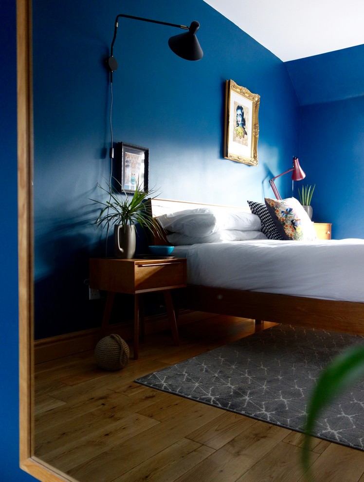 Idées déco pour une chambre parentale rétro de taille moyenne avec un mur bleu et parquet clair.
