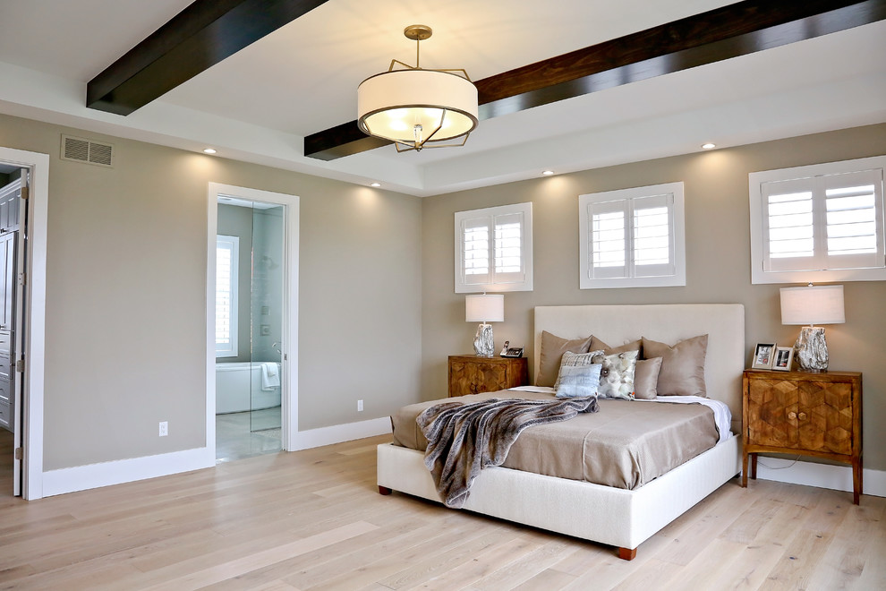 Modelo de dormitorio principal clásico renovado grande con paredes beige y suelo de madera clara