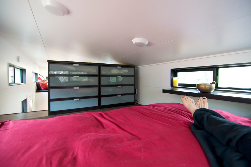 Idéer för ett litet modernt sovloft, med vita väggar och mellanmörkt trägolv