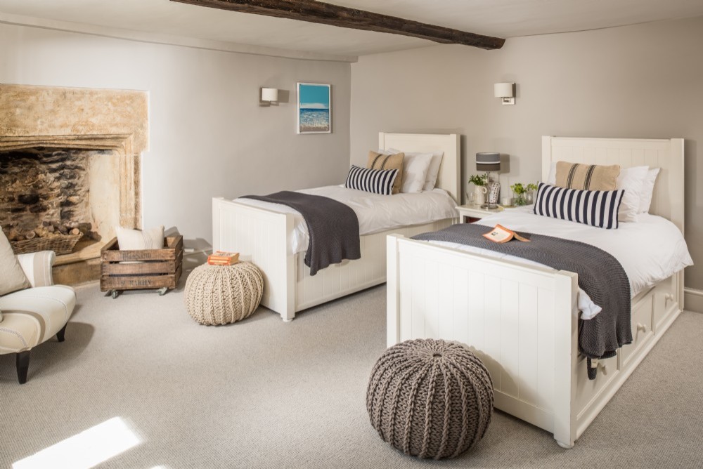 Design ideas for a medium sized classic guest bedroom in Dorset with beige walls, carpet, a standard fireplace, a stone fireplace surround and grey floors.