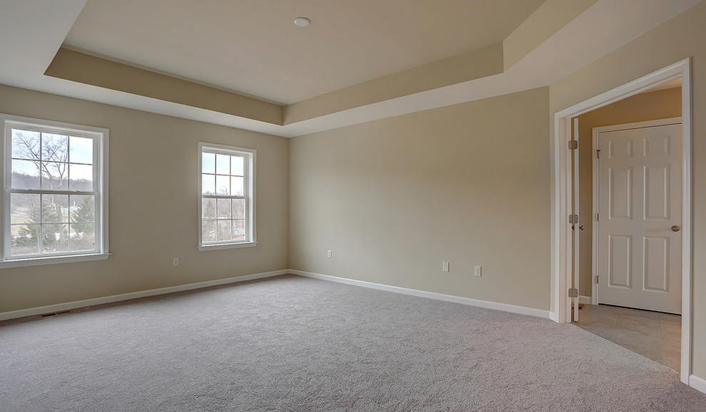 Réalisation d'une grande chambre tradition avec un mur beige et un sol beige.