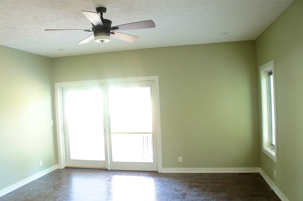 Inspiration pour une chambre parentale craftsman de taille moyenne avec un mur vert et un sol en bois brun.