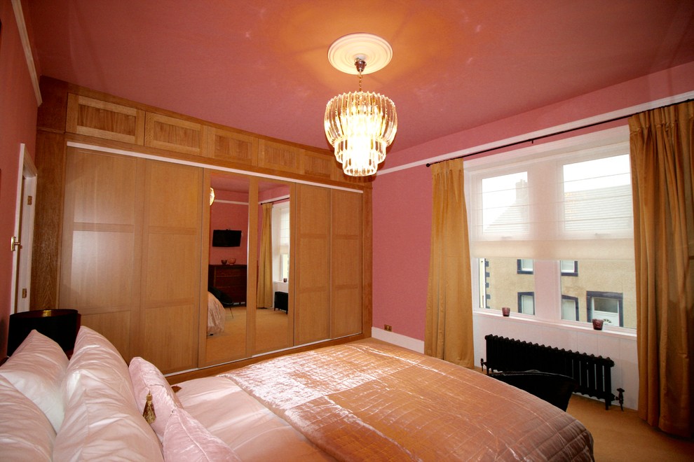 На фото: большая хозяйская спальня в стиле фьюжн с розовыми стенами, ковровым покрытием, стандартным камином и фасадом камина из штукатурки с