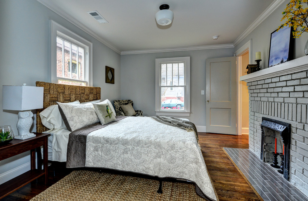Inspiration for a small timeless guest medium tone wood floor bedroom remodel in Atlanta with gray walls, a standard fireplace and a brick fireplace