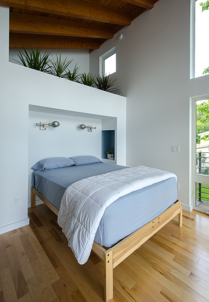 Cette photo montre une chambre parentale tendance de taille moyenne avec un mur blanc, un sol en bois brun et un sol jaune.