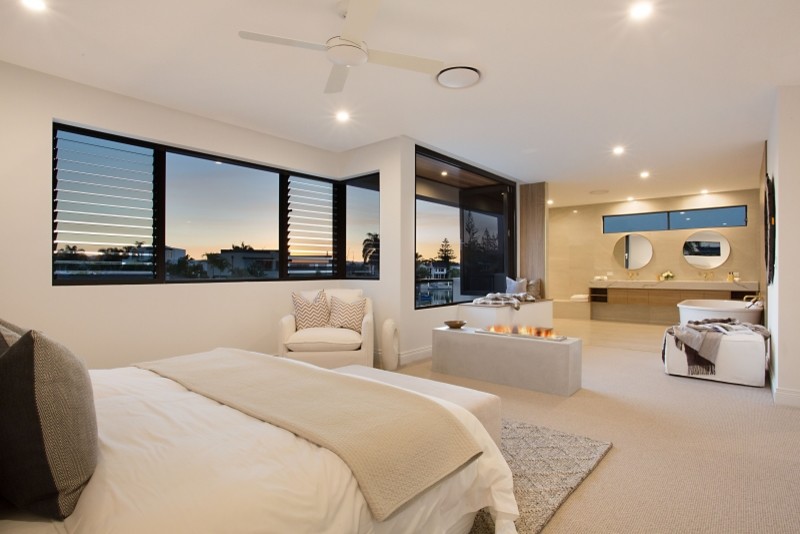 Diseño de dormitorio principal minimalista grande con paredes blancas, moqueta, chimenea de doble cara, marco de chimenea de hormigón y suelo beige