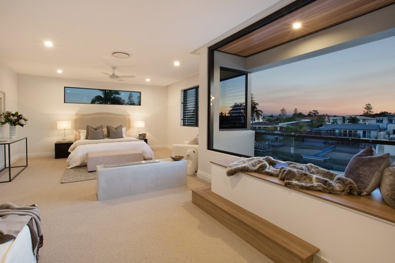 Diseño de dormitorio principal moderno grande con paredes blancas, moqueta, chimenea de doble cara, marco de chimenea de hormigón y suelo beige