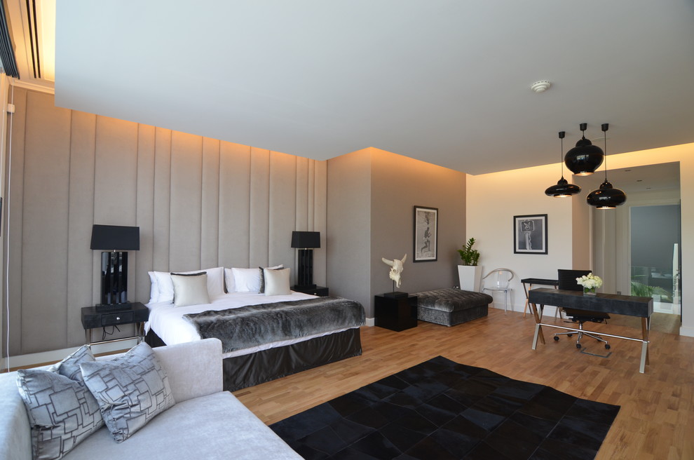 Imagen de dormitorio actual con paredes grises, suelo de madera en tonos medios y con escritorio