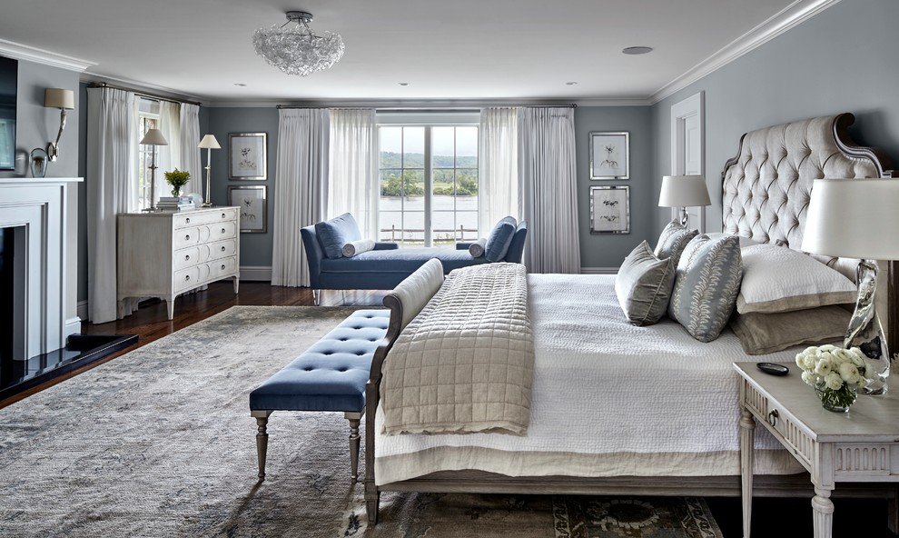 Großes Maritimes Hauptschlafzimmer mit grauer Wandfarbe, braunem Holzboden, Kamin, Kaminumrandung aus Stein und braunem Boden in Bridgeport