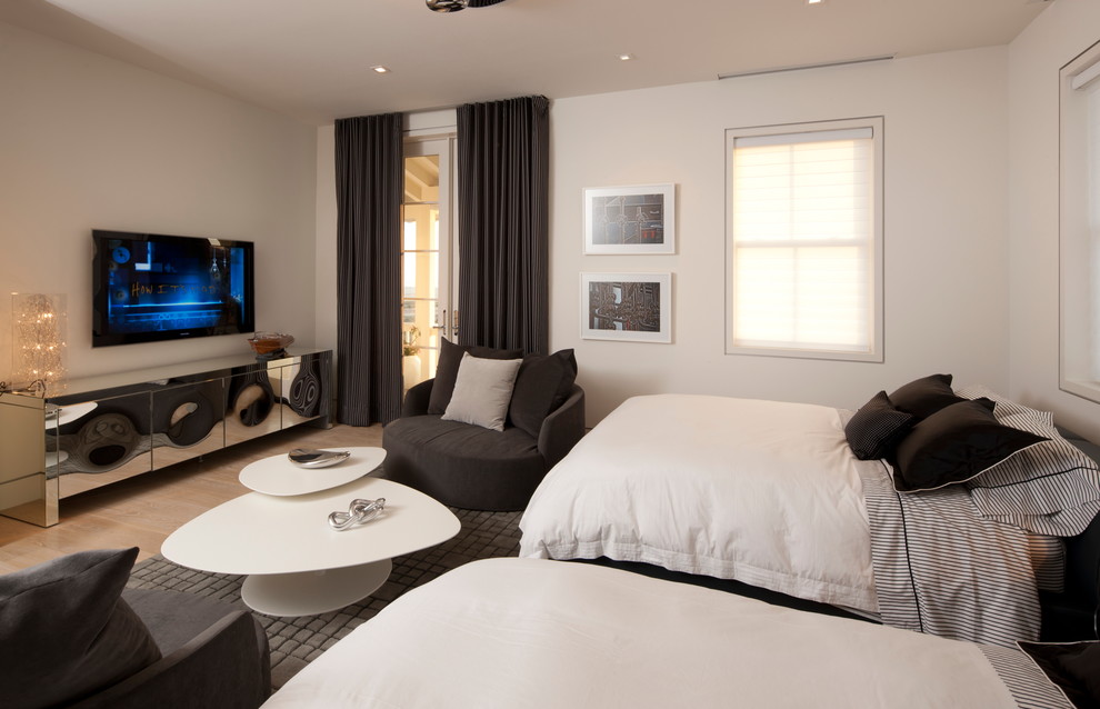 Diseño de habitación de invitados actual sin chimenea con paredes blancas y suelo de madera clara