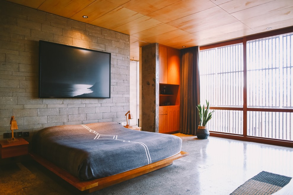 Foto di una camera da letto tropicale con pareti grigie, pavimento in cemento e pavimento grigio