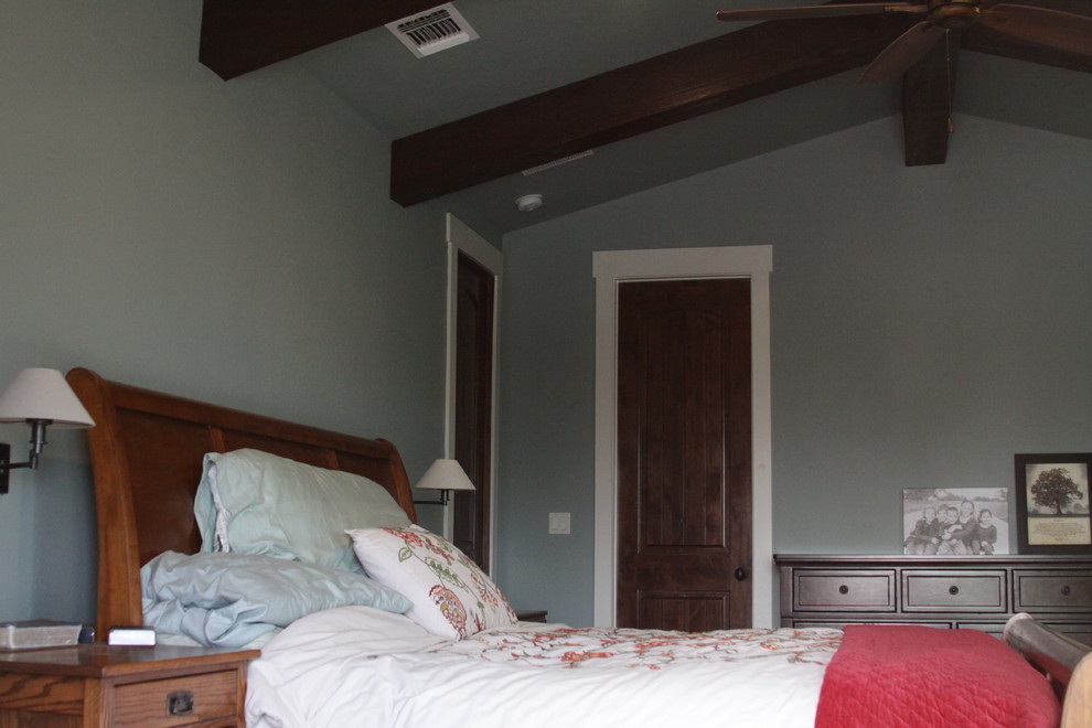 Foto de dormitorio principal rústico grande con paredes azules, suelo de cemento y marco de chimenea de piedra