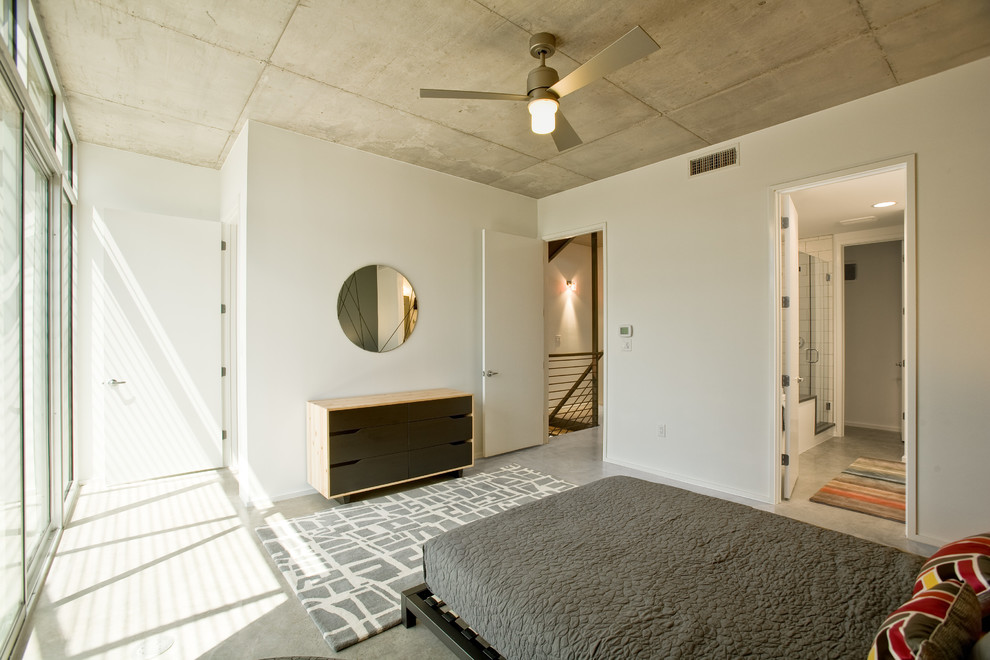 Imagen de dormitorio actual con suelo de cemento y paredes blancas