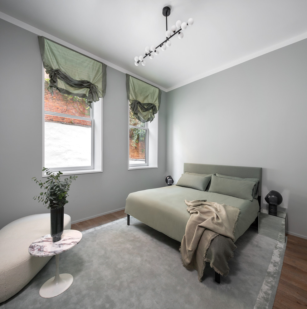 Exemple d'une grande chambre parentale tendance avec un mur vert, parquet clair, aucune cheminée et un sol marron.