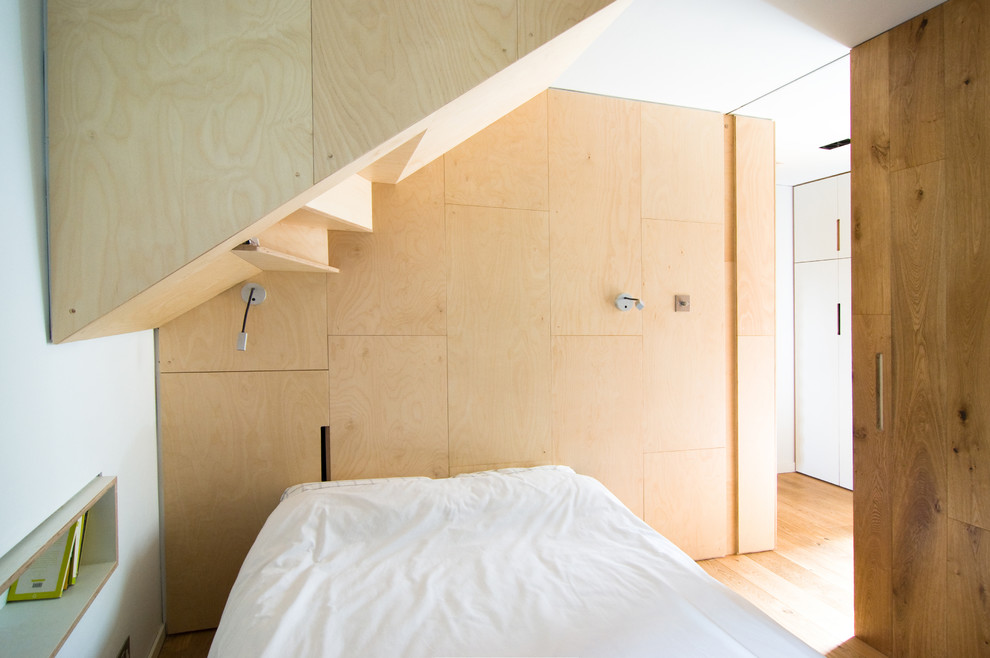 This is an example of a small contemporary guest bedroom in London with plywood flooring.