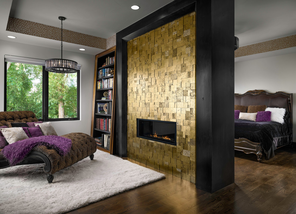 Modelo de dormitorio contemporáneo con paredes blancas, suelo de madera oscura, chimenea lineal, marco de chimenea de baldosas y/o azulejos y suelo marrón