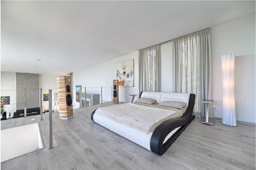 Ejemplo de dormitorio tipo loft actual con paredes blancas y suelo gris