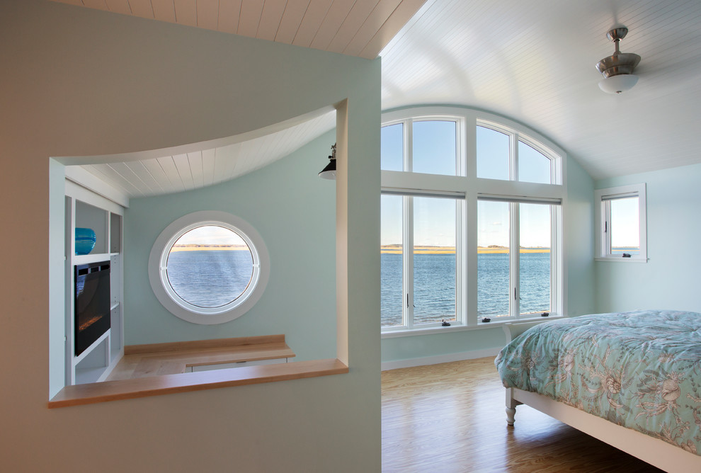 На фото: хозяйская спальня среднего размера в морском стиле с синими стенами, светлым паркетным полом, горизонтальным камином и фасадом камина из дерева с