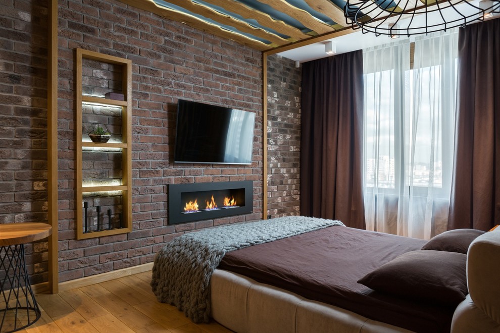 Inspiration pour une chambre parentale chalet de taille moyenne avec un mur multicolore, parquet clair, une cheminée standard et un manteau de cheminée en brique.