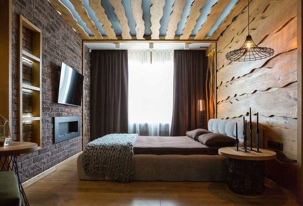 На фото: хозяйская спальня среднего размера в стиле рустика с разноцветными стенами, светлым паркетным полом, стандартным камином и фасадом камина из кирпича