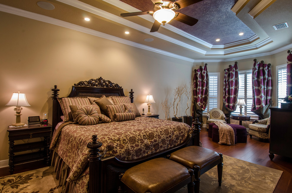 Diseño de dormitorio principal tradicional grande sin chimenea con paredes beige, suelo de madera en tonos medios y suelo marrón