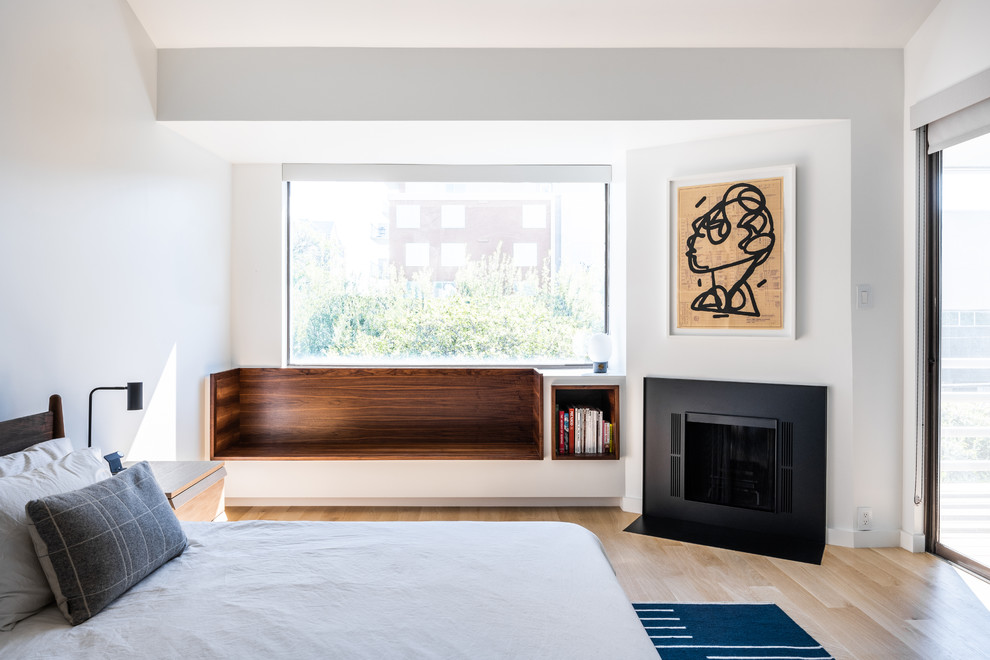Esempio di una camera da letto design con pareti bianche, parquet chiaro, camino classico e pavimento beige