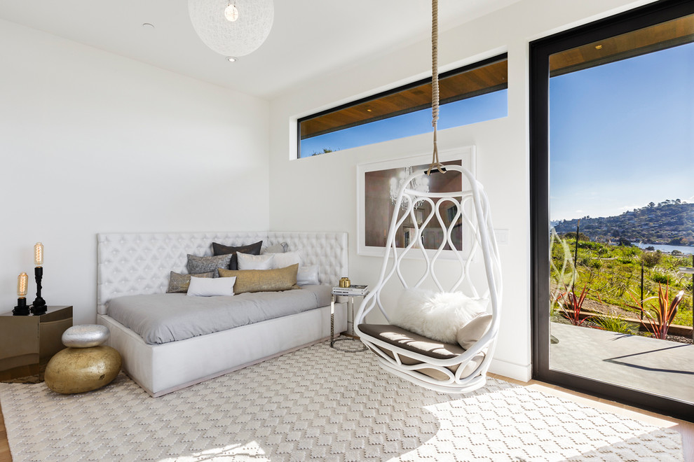 Esempio di una camera da letto design con pareti bianche, parquet chiaro e cornice del camino in mattoni