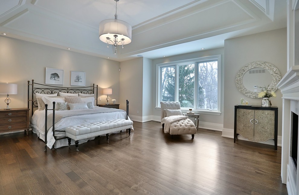 Стильный дизайн: хозяйская спальня в классическом стиле с серыми стенами, паркетным полом среднего тона и стандартным камином - последний тренд