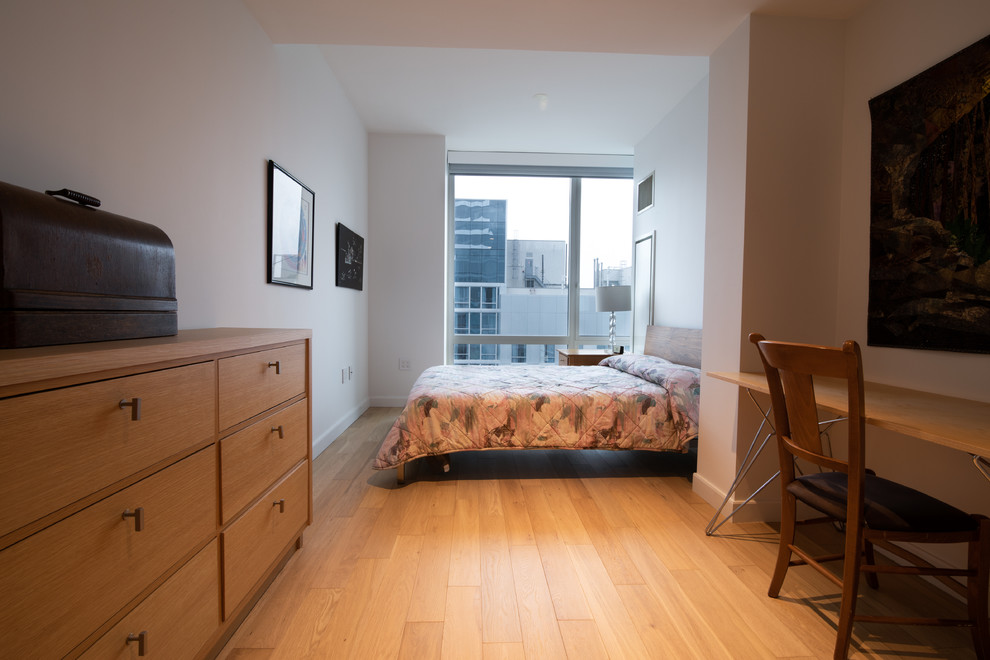 Esempio di una camera degli ospiti minimalista con pareti bianche, parquet chiaro e pavimento giallo