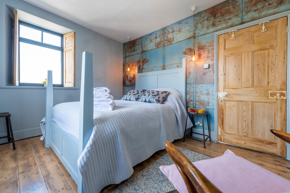 Example of a mid-sized urban medium tone wood floor and brown floor bedroom design in Cornwall with blue walls