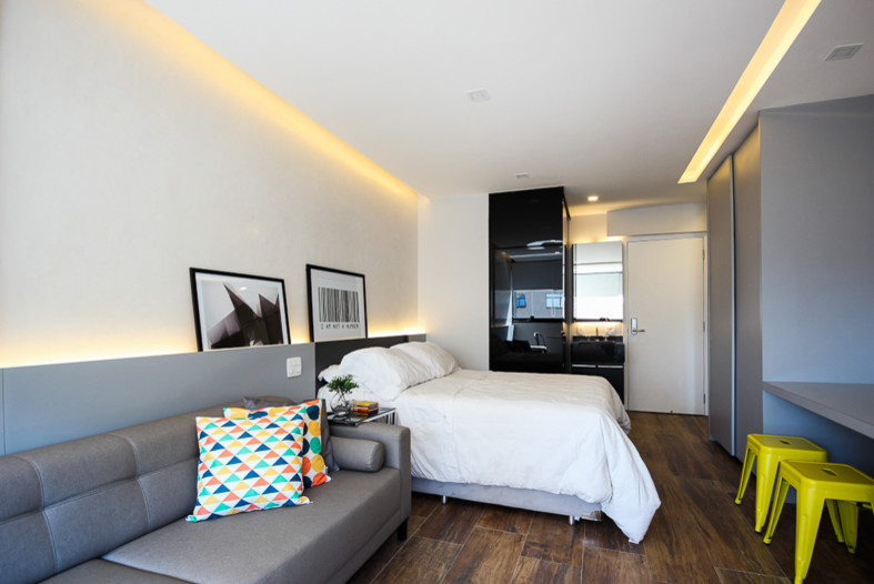 Diseño de dormitorio tipo loft contemporáneo pequeño con paredes grises, suelo de baldosas de porcelana y suelo marrón
