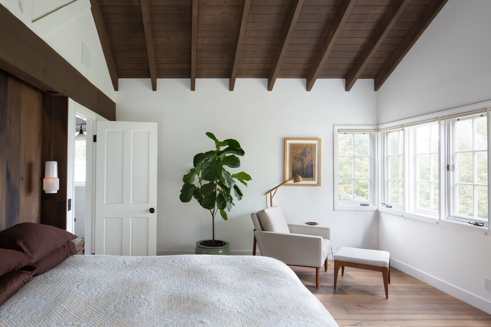 Diseño de dormitorio campestre con paredes blancas, suelo de madera en tonos medios y suelo marrón