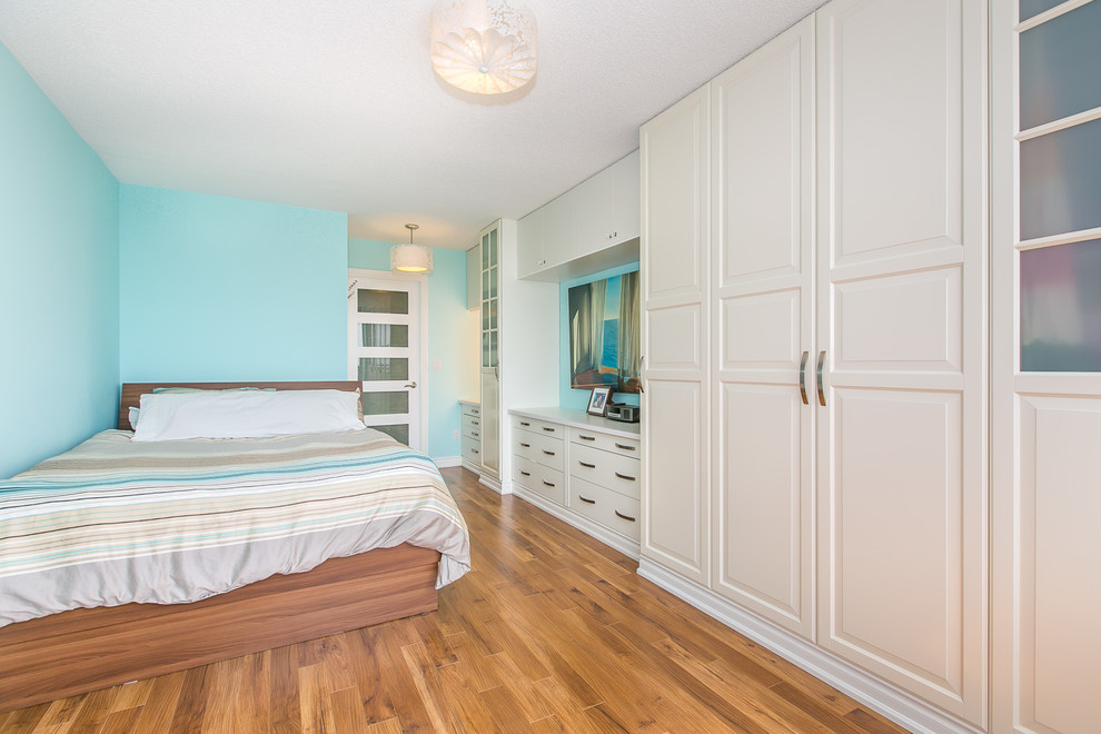 Cette photo montre une chambre parentale tendance de taille moyenne avec un mur bleu et un sol en bois brun.