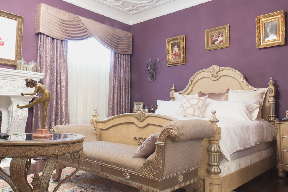 Esempio di una camera da letto tradizionale con pareti viola, parquet scuro, camino classico e cornice del camino in intonaco