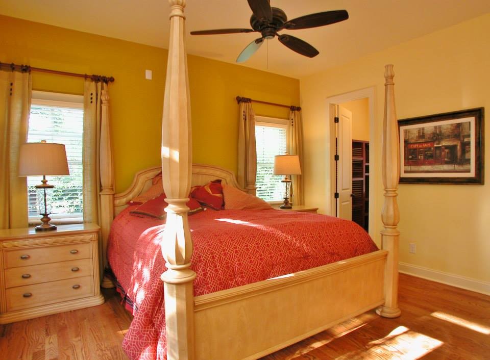 Diseño de dormitorio principal tradicional grande con paredes amarillas y suelo de madera en tonos medios