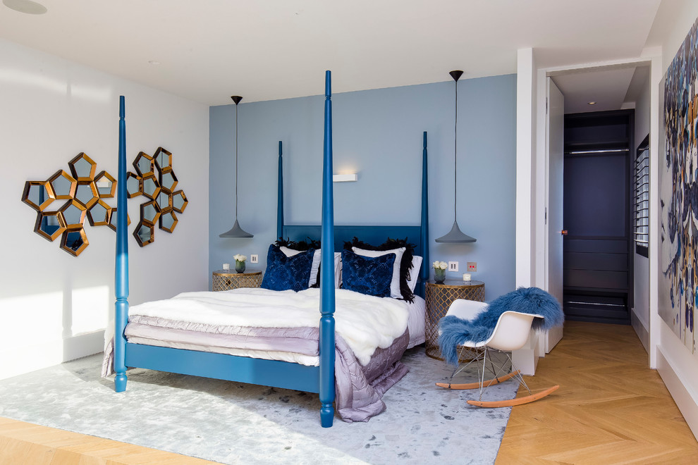 Diseño de dormitorio actual con paredes azules, suelo de madera en tonos medios y suelo marrón
